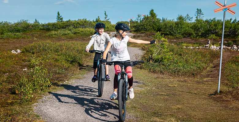 Bilden visar två barn som cyklar i fjällen