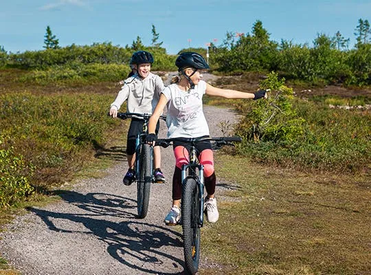 Bilden visar två barn som cyklar i fjällen
