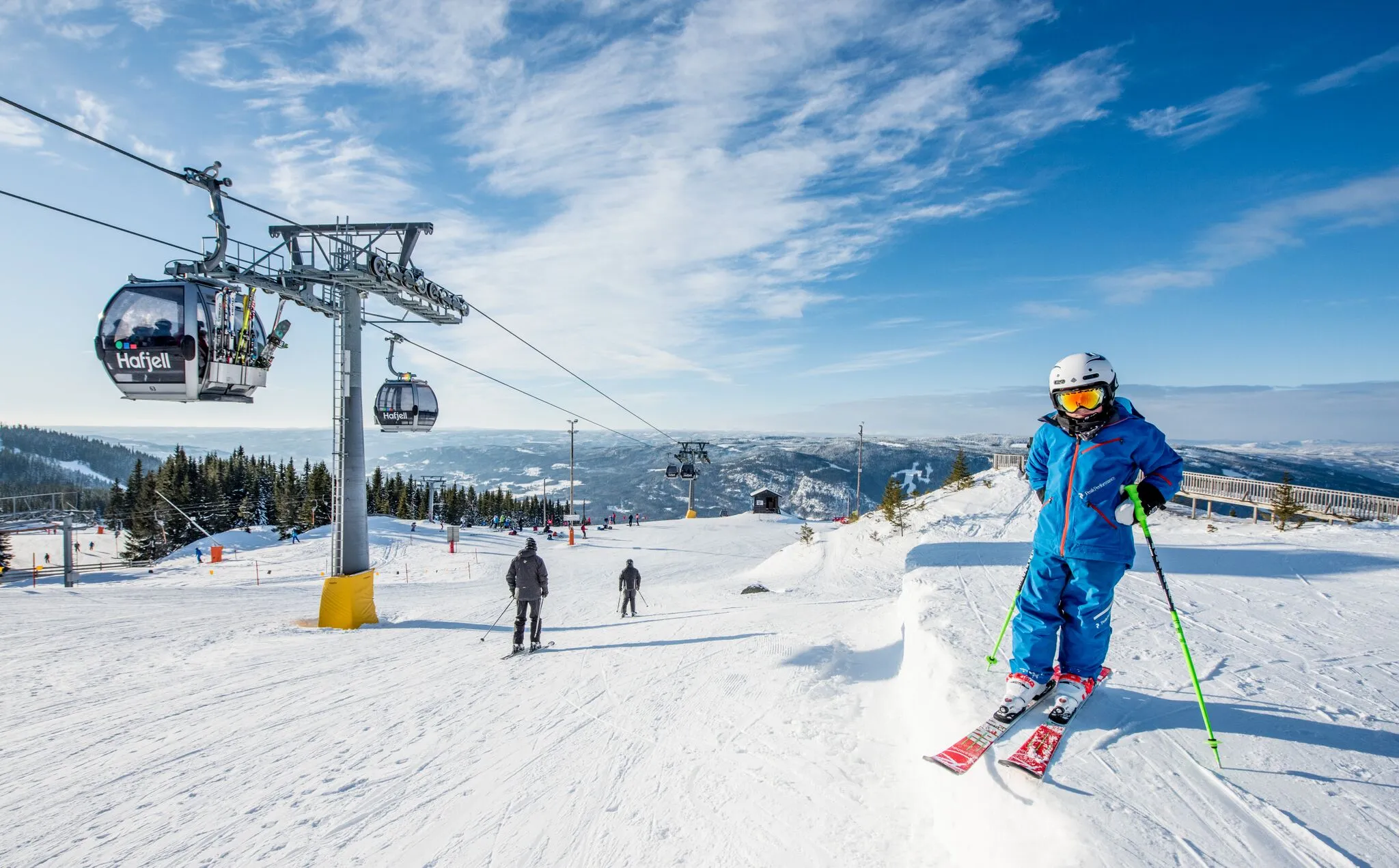 Bilden visar ett soligt Hafjell med liftar och skidåkare