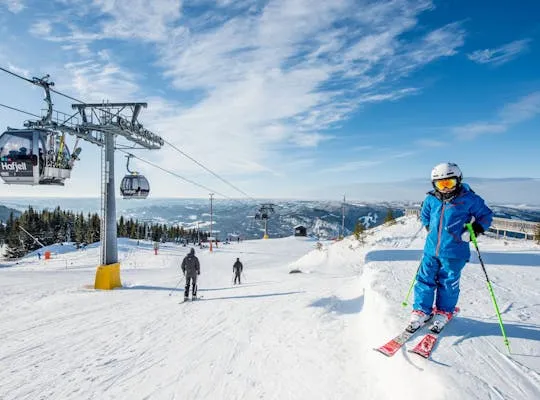 Bilden visar ett soligt Hafjell med liftar och skidåkare