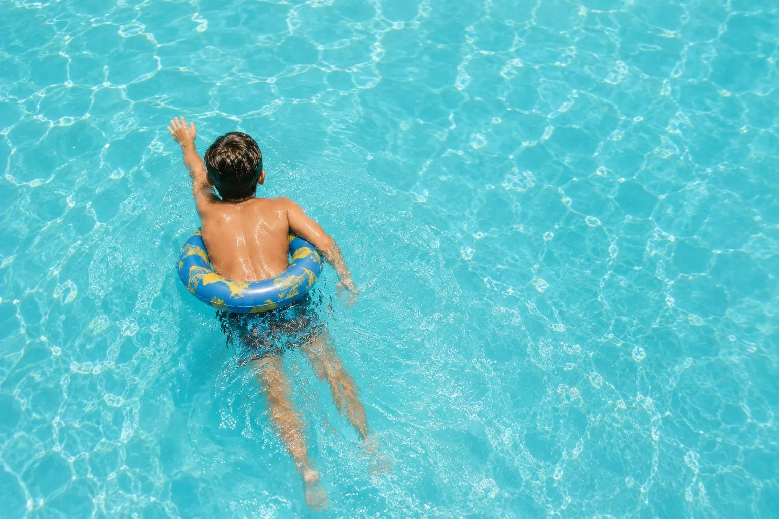 Bilden visar en pojke inuti en badring som simmar i en pool